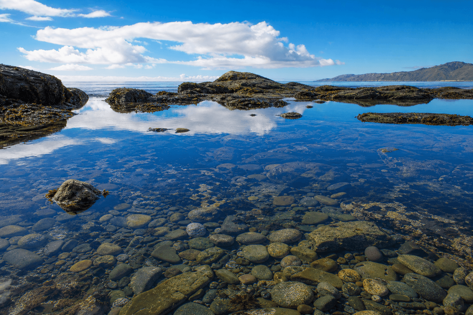 Clear crystal tide pool reflecting a bright blue sky representing clarity and grounded reality in schizophrenia treatment